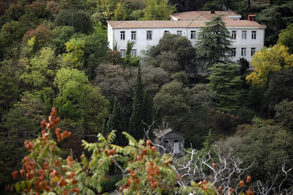 Historic building nestled among autumn trees in Tbilisi's National Botanical Garden.