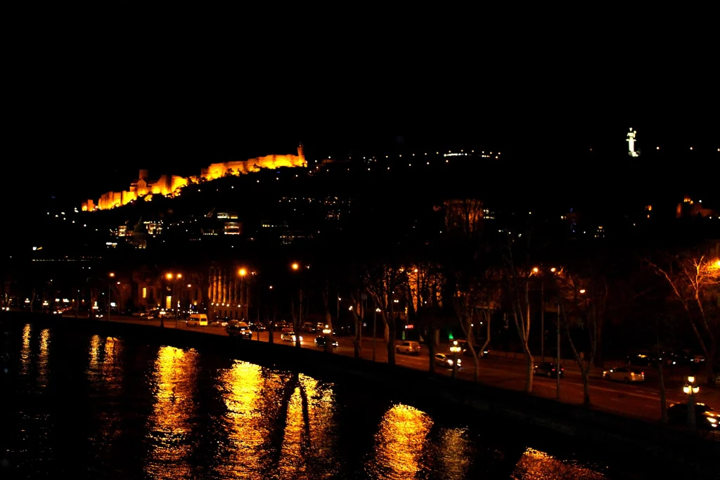 Narikala fortress illuminated at night above the Tbilisi skyline during blue hour.