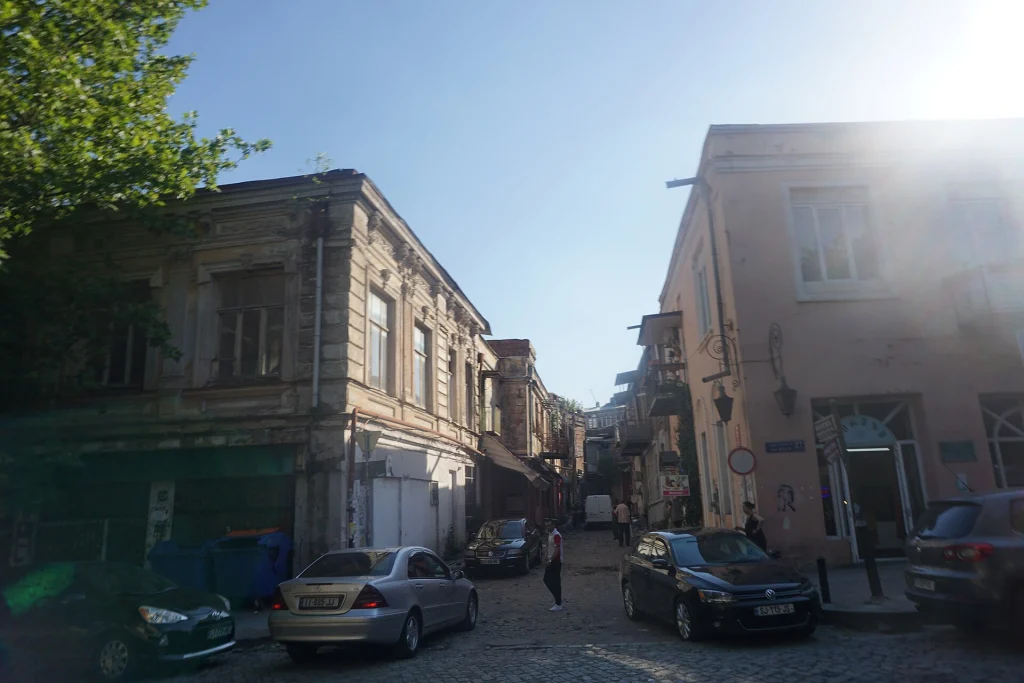 A sunlit cobblestone street in Tbilisi's Old Town shows the city's everyday atmosphere.
