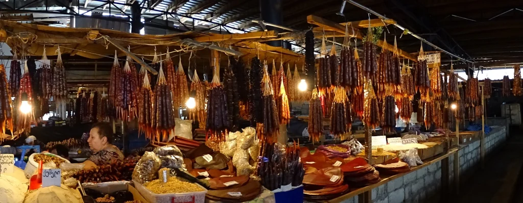 Rows of churchkhela and sweets hang above market stalls in a Georgian bazaar.