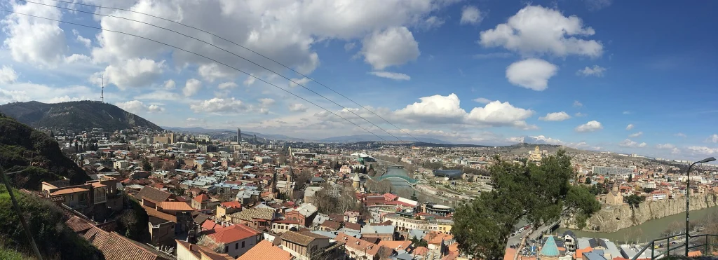 Wide panorama of Tbilisi's old town with the Kura River and bridges.