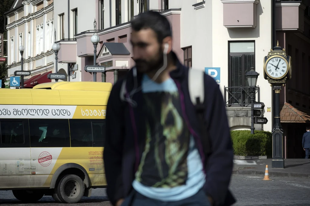 Pedestrians and a public bus on an Old Tbilisi street, illustrating urban Georgia for travellers.