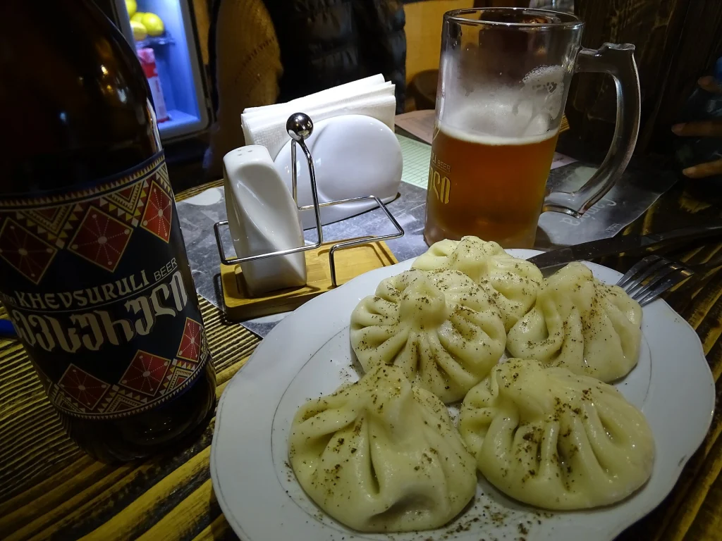 A plate of khinkali dumplings with local beer, the hearty fare travellers encounter in Kazbegi.