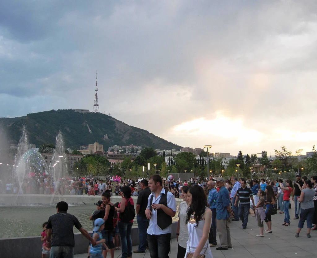 Families gather by the fountain and playground in Rike Park beneath Mtatsminda hill.