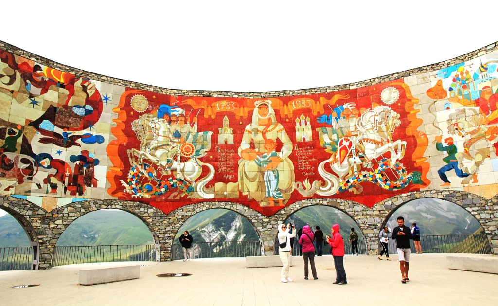 Visitors view the colourful inner mosaic of horsemen and figures inside the monument's curved wall.