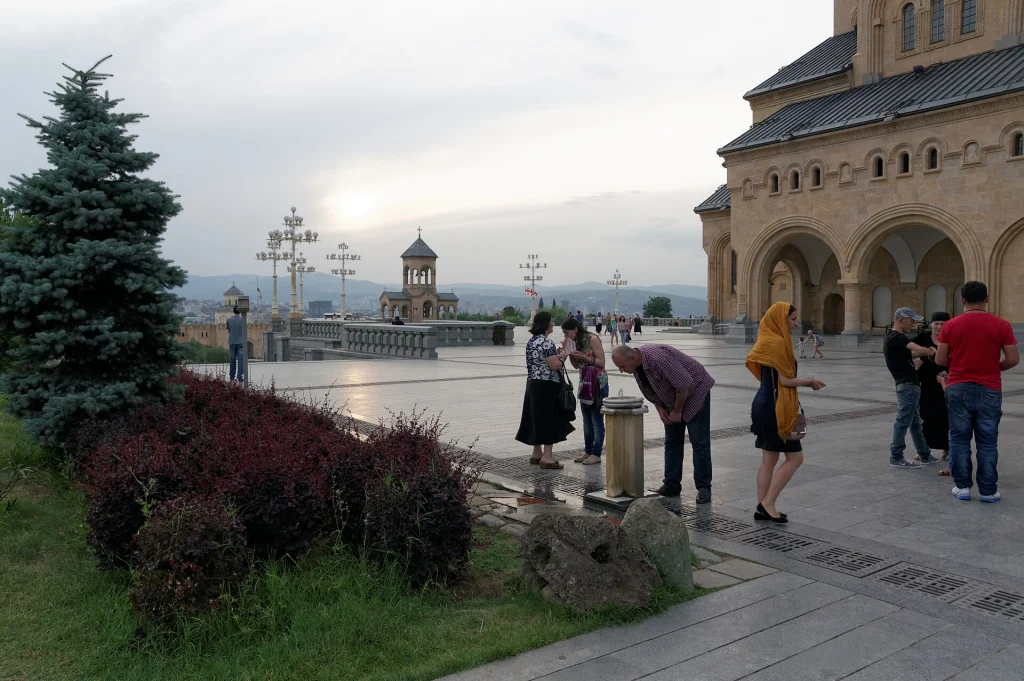 Visitors stroll the plaza outside Holy Trinity Cathedral, a typical scene for tourists in Tbilisi.