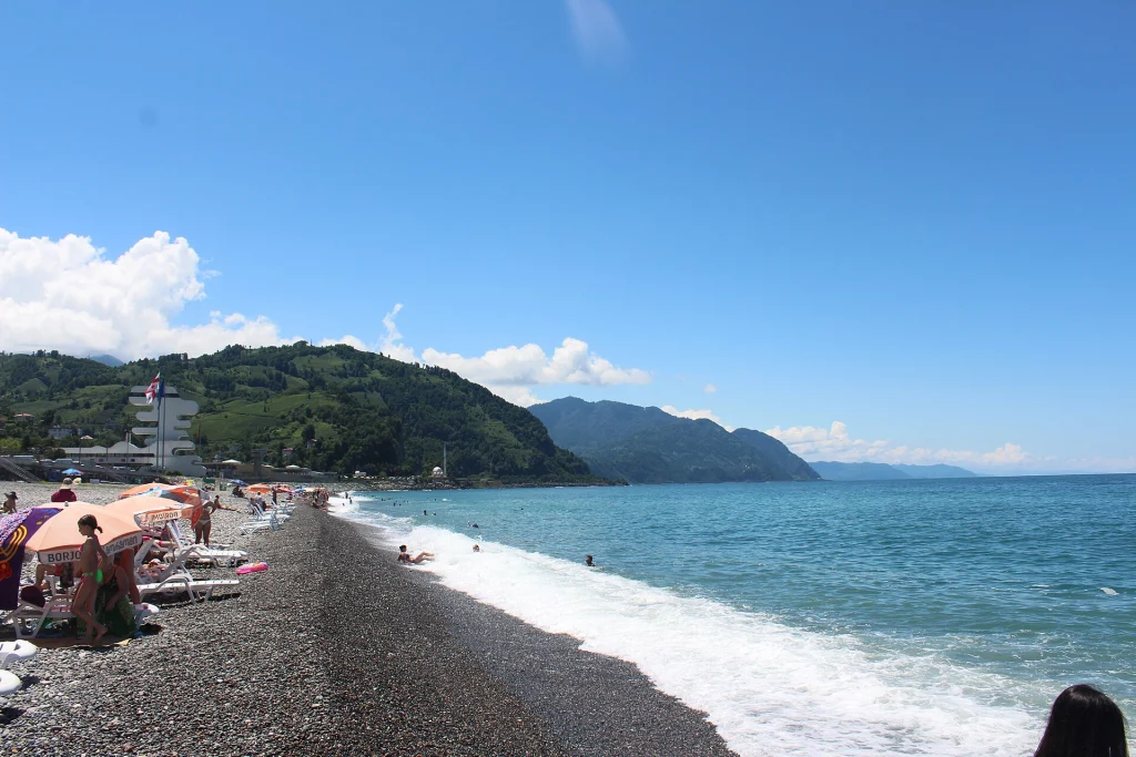 Visitors relax on Sarpi's pebble beach along the Black Sea coast.