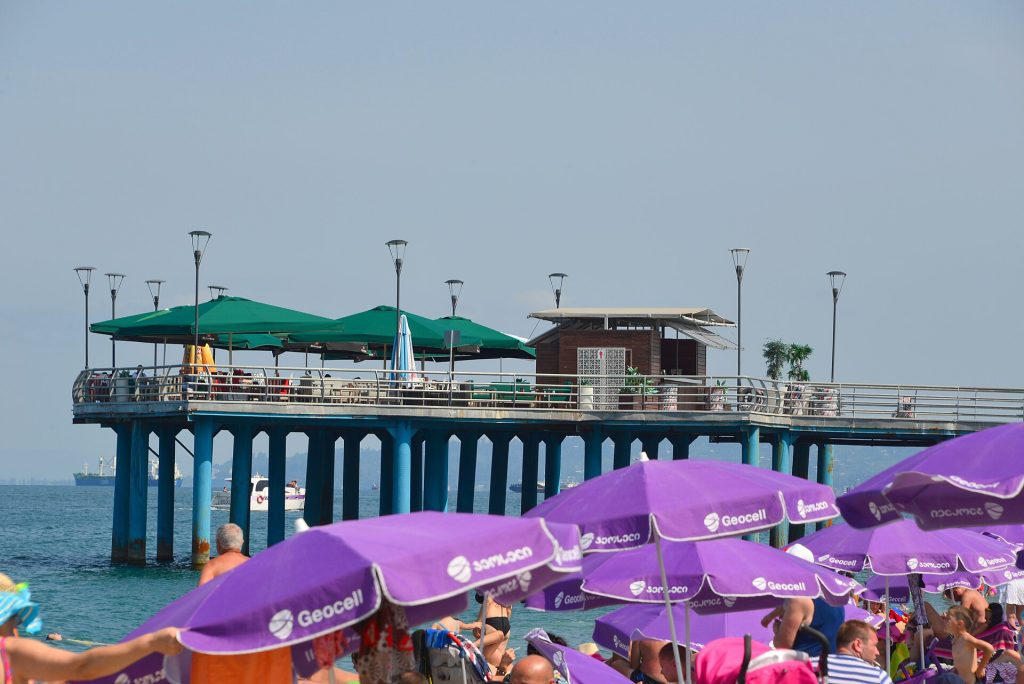 Crowds relax under purple beach umbrellas on Batumi's seafront promenade during the season's opening.