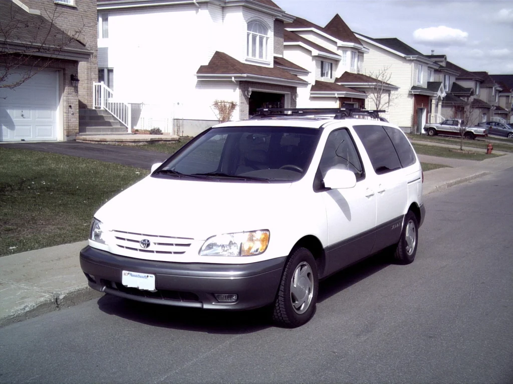 A white Toyota Sienna minivan parked on a quiet street, illustrating a private transfer vehicle.