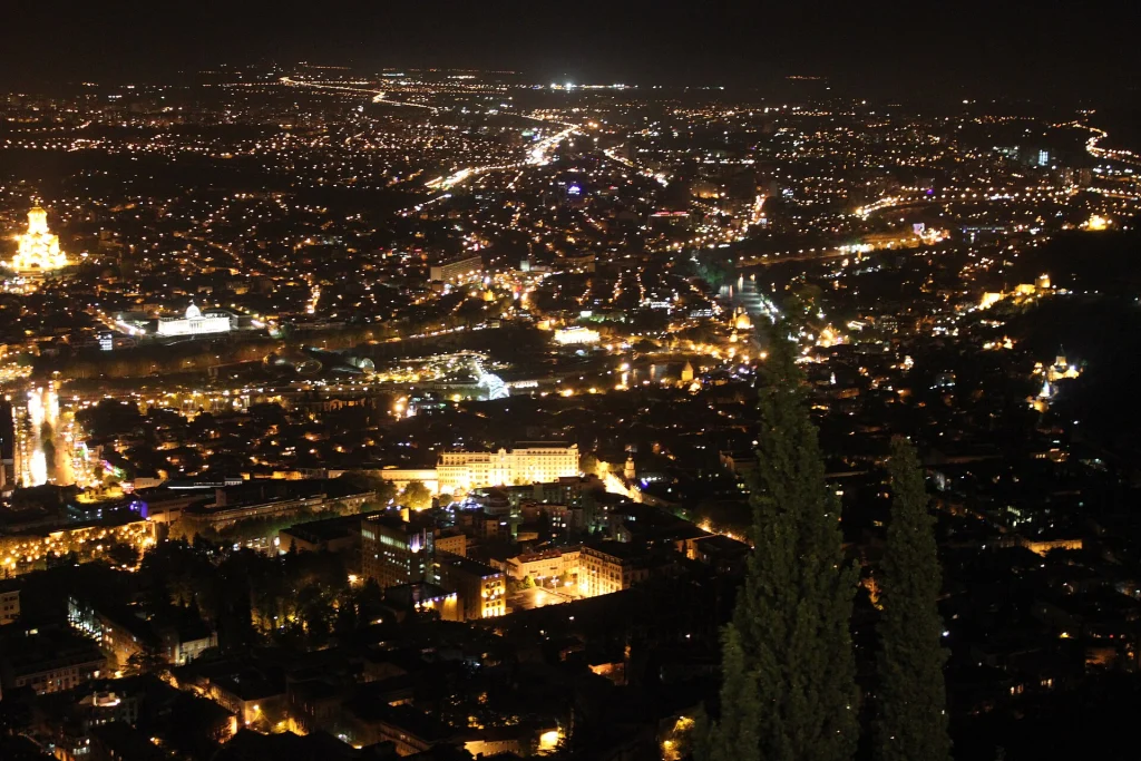 Tbilisi's skyline glittering at night, seen from Mtatsminda hill above the city.
