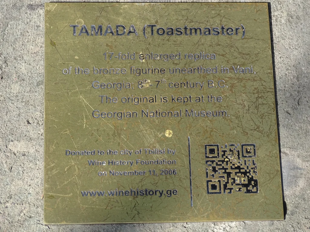 A Tbilisi plaque explains the tamada toastmaster tradition central to Georgian feasts.