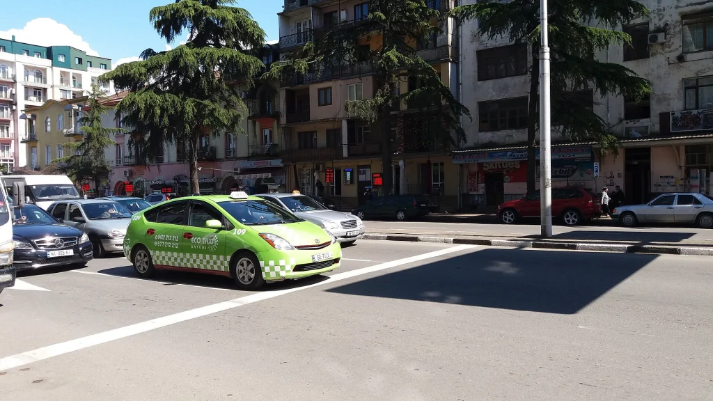 Такси, включая маркированные автомобили, выстроились вдоль улицы в Батуми, Грузия.