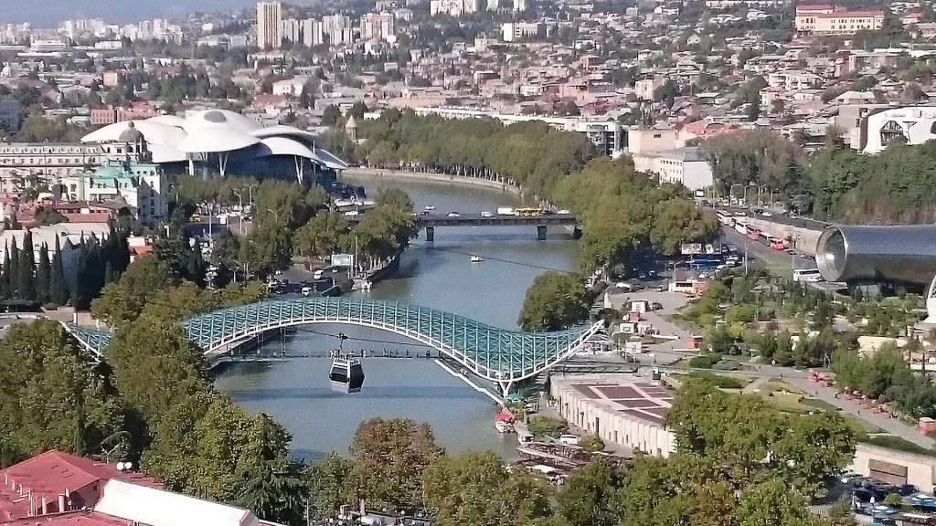 Aerial view of Tbilisi with the river, bridge and cable car line in the foreground.