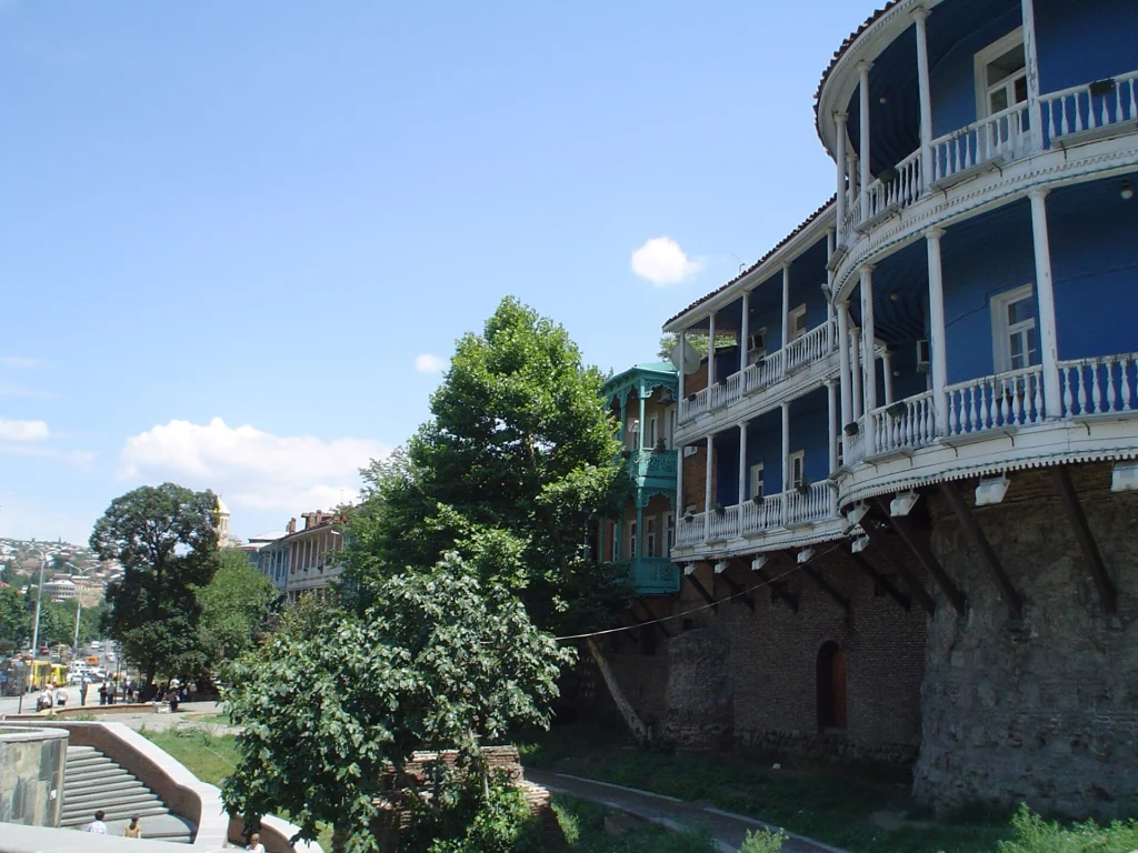 A traditional blue balcony house perches atop the old city wall in Tbilisi's historic quarter.
