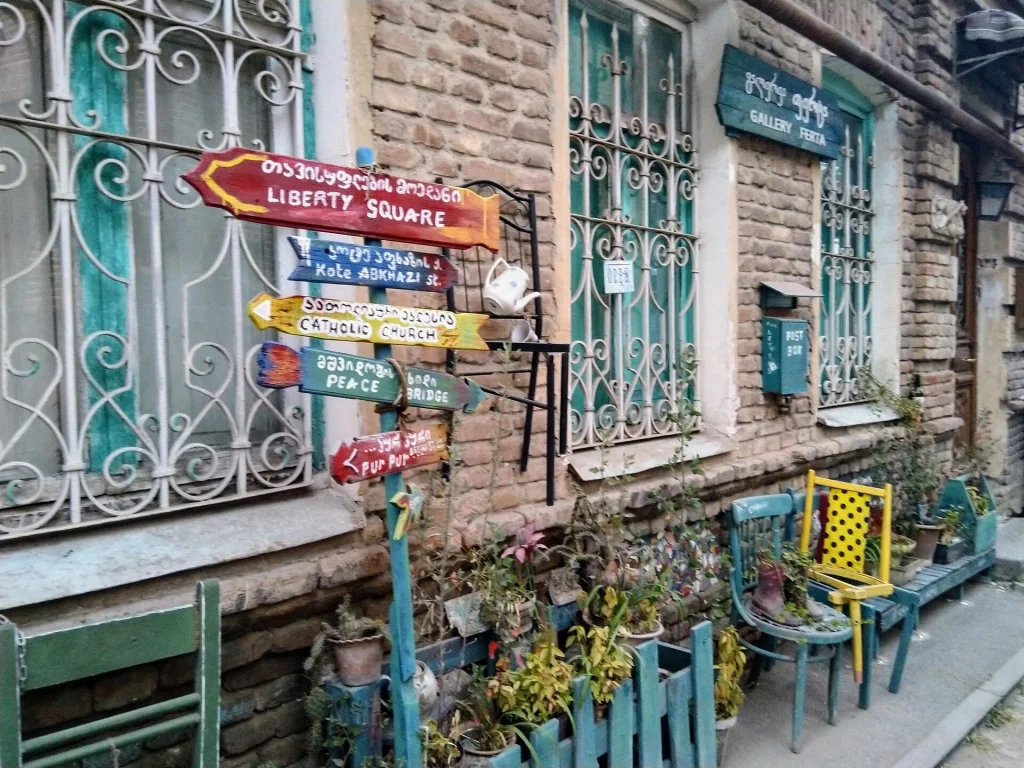 A colourful lane in Tbilisi's Old Town with directional signposts for tourists.