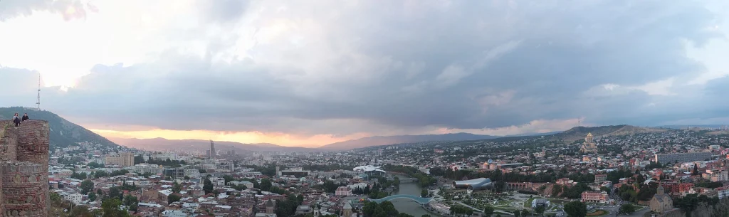 Panoramic dusk view of Tbilisi taken from Narikala fortress at golden hour.