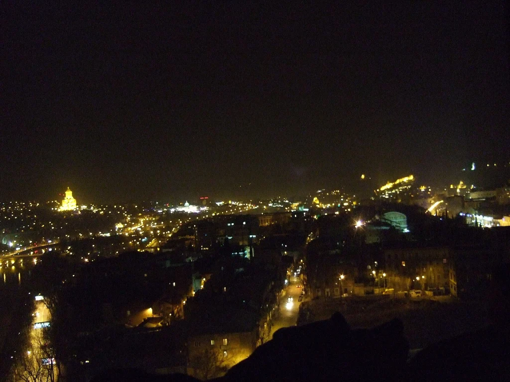 Night view of Tbilisi, Georgia's capital, with illuminated cityscape along the river.
