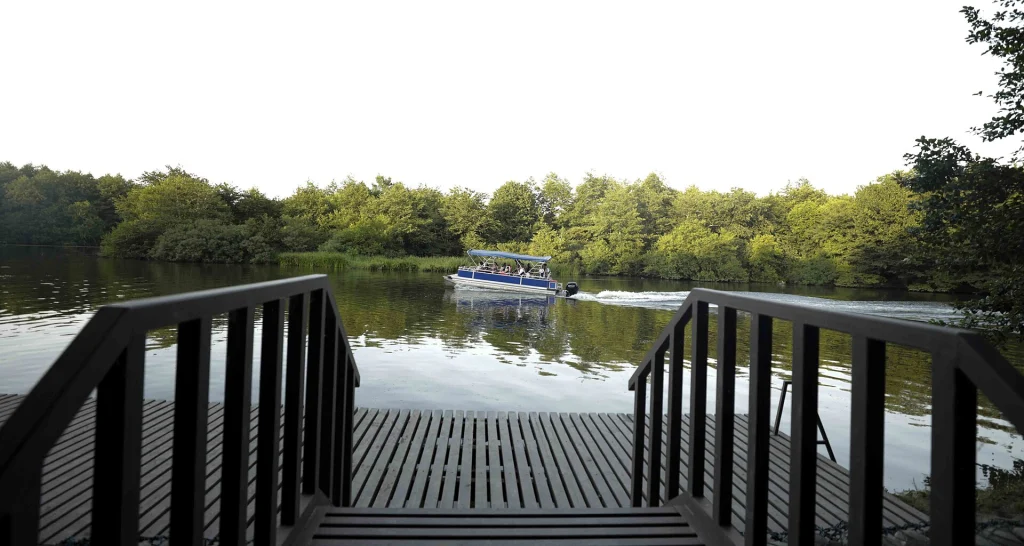 A boat heads along a tree-lined estuary toward Lake Paliastomi.