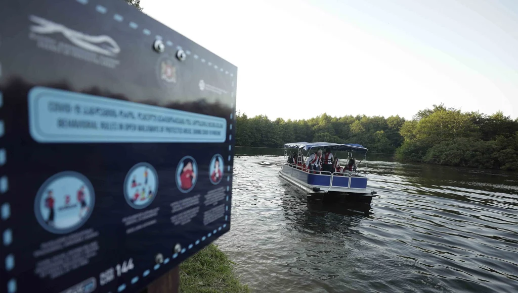 Tourists ride a boat across the calm waters of Lake Paliastomi.