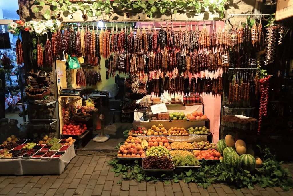 Traditional Georgian market stall displaying hanging churchkhela, fresh fruit and vegetables.