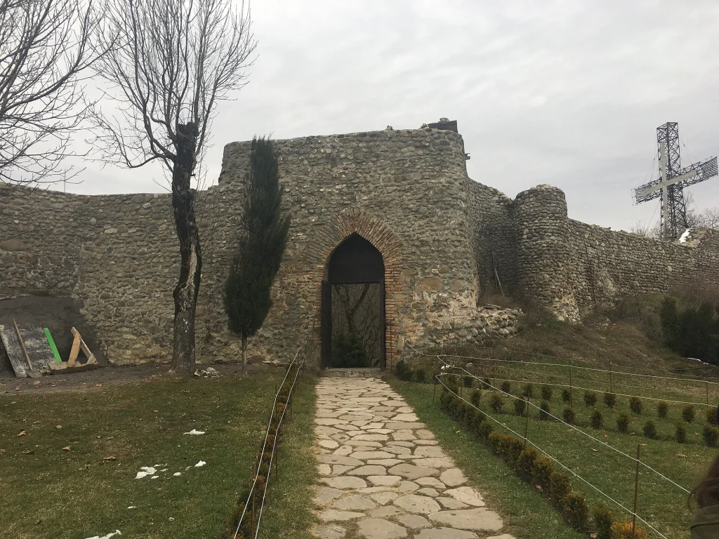 The fortified gate and cross mark the entrance to Zedazeni Monastery grounds.