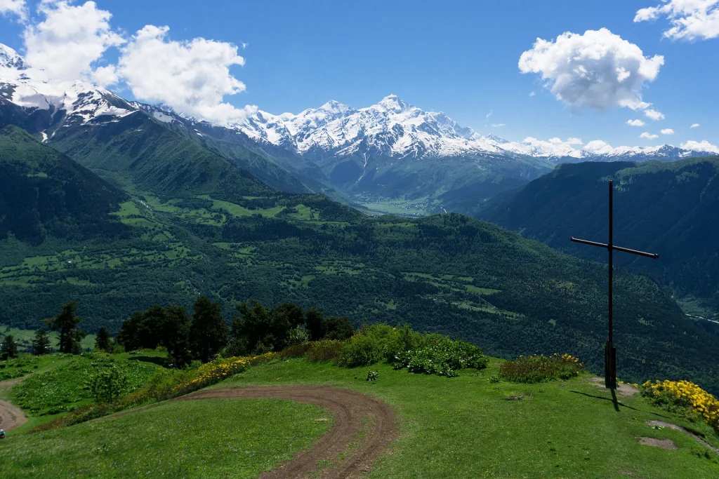 A green Svaneti valley with snow-capped peaks beyond, showing the dramatic terrain near Mestia.