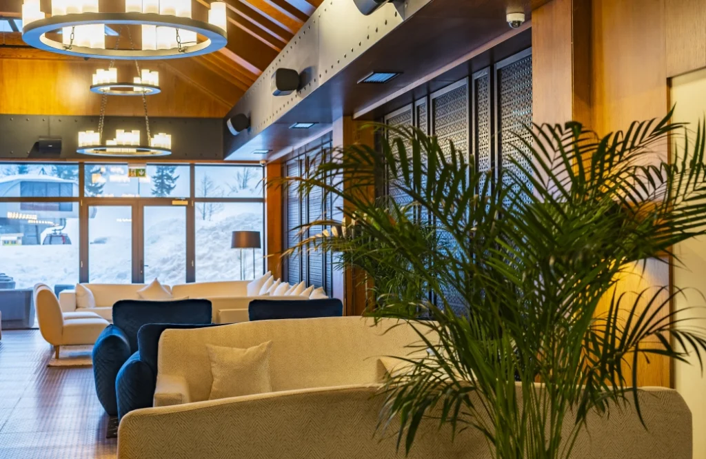 A la Carte Restaurant — Cozy lounge area with sofas, palm plant, and large windows overlooking snowy exterior.