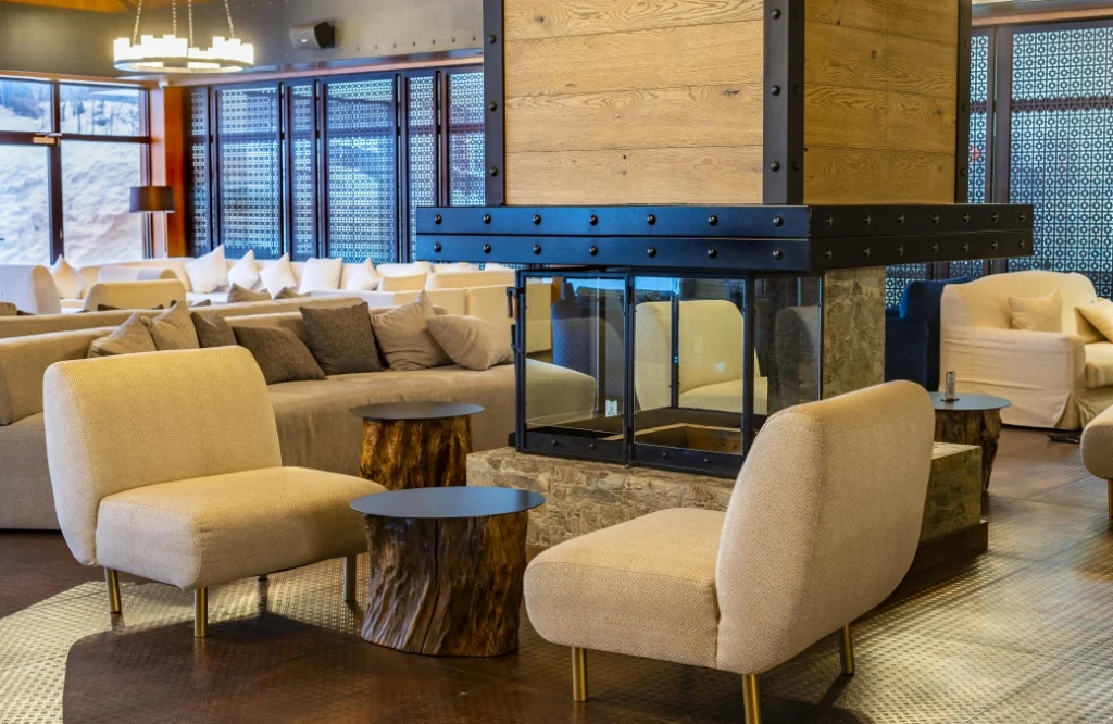 A la Carte Restaurant — Cozy fireplace lounge area with beige armchairs and sofas.
