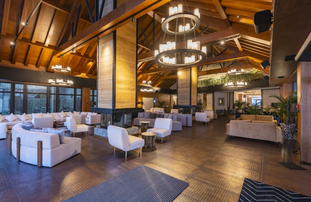 A la Carte Restaurant — Lounge with high wooden beamed ceiling, chandeliers, and white seating arrangements.