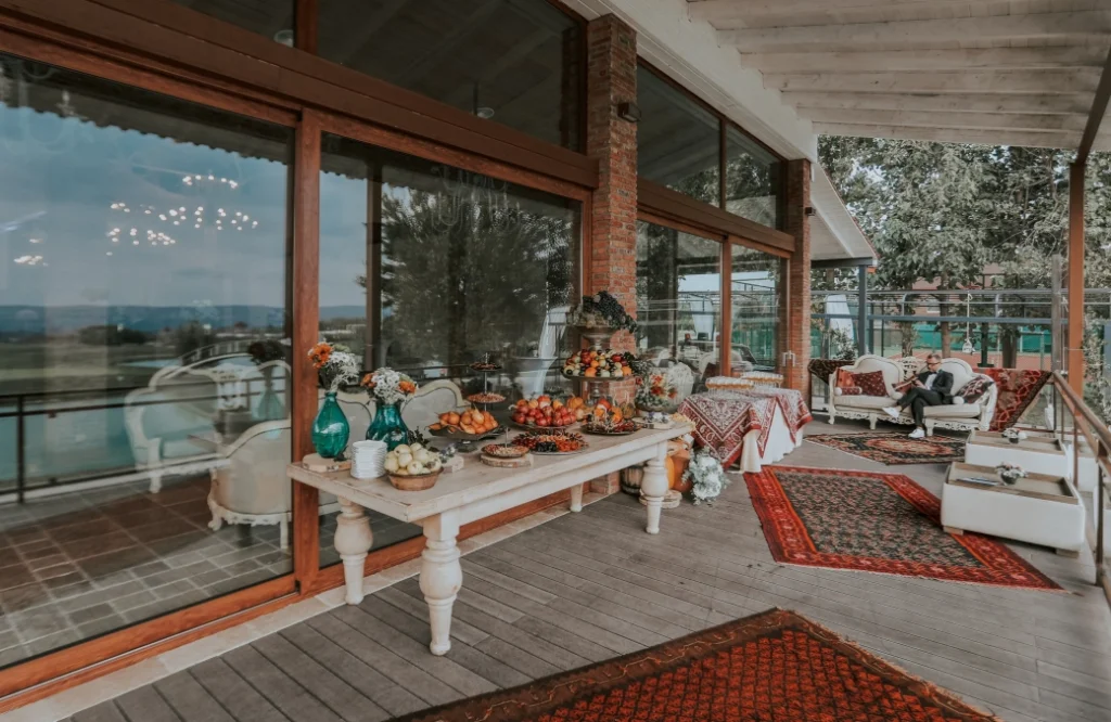Banquet Hall — Covered terrace lounge area with seating and a decorative table offering outdoor views.