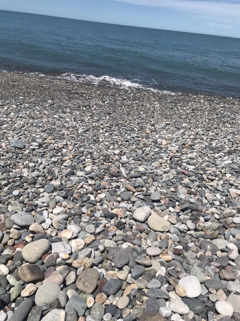 Smooth pebbles line the shoreline of a sunny Batumi beach.