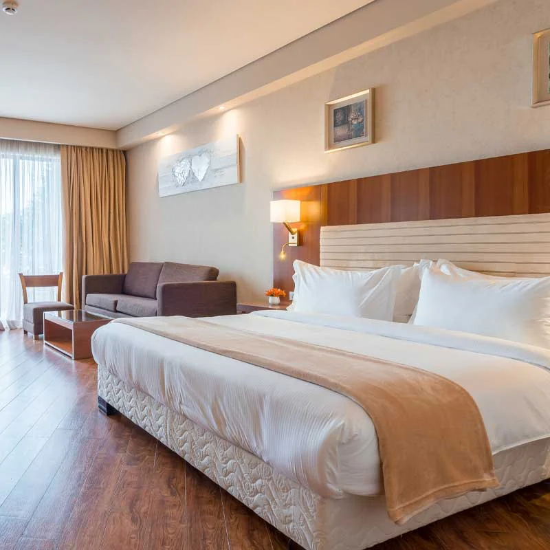 Beach Bar — Spacious hotel room with a king bed, sofa, and wood flooring.