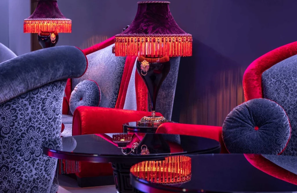 Club — Close-up seating area with plush velvet armchairs and ornate fringed lamp.