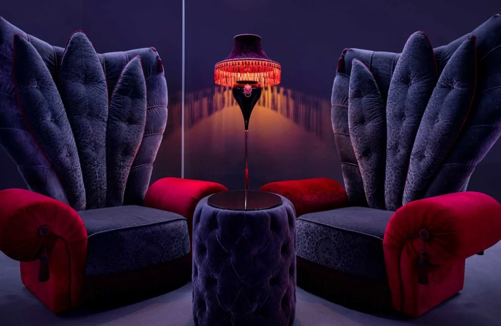 Club — Two dramatic wingback velvet chairs facing each other with a glowing lamp between them.