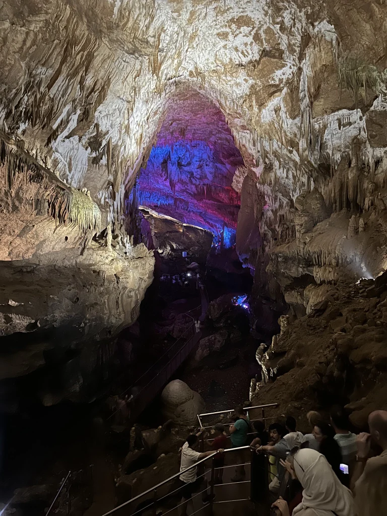 A group of tourists walks a lit walkway deep inside Prometheus Cave.