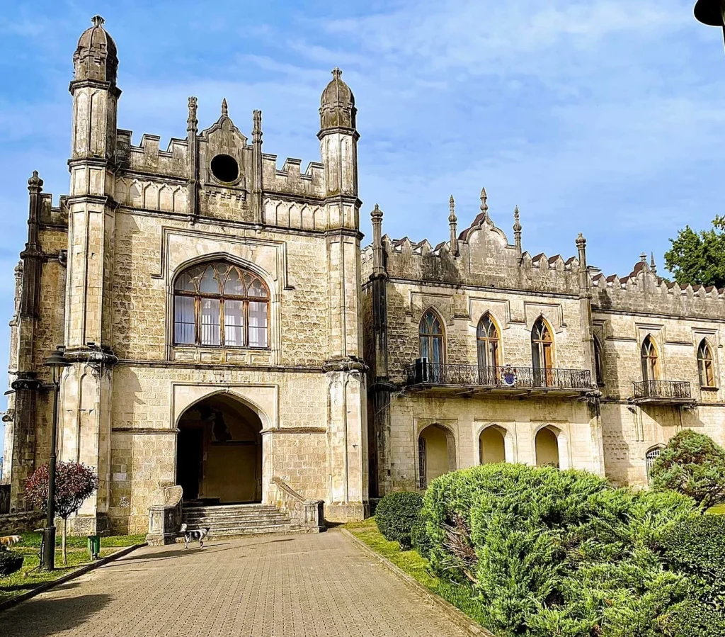 Facade of the historic Dadiani Palace Museum in Zugdidi under a blue sky.