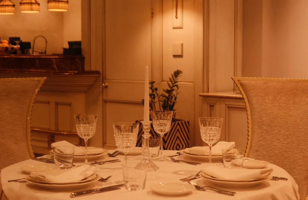 Daira Restuarant — Intimate table setting with crystal glassware and candle in a softly lit dining room.