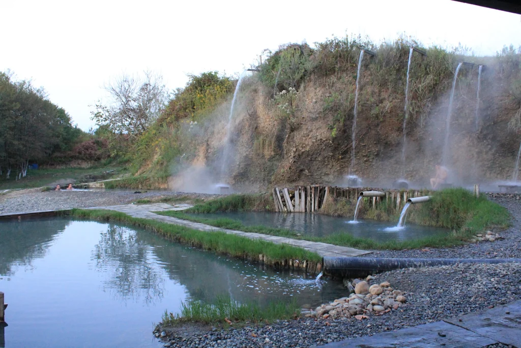 Bathers soak in cascading natural hot-spring pools fed by warm waterfalls near Gulripshi.