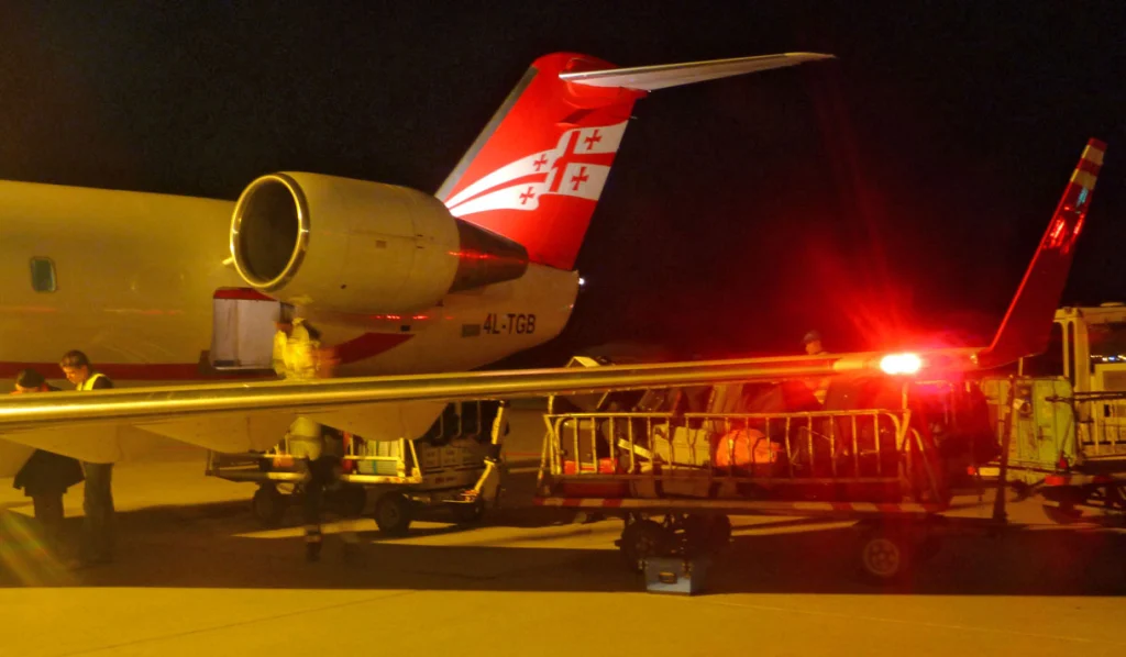 Night ground handling of an Air Zena aircraft with Georgian tail livery, typical of late arrivals.