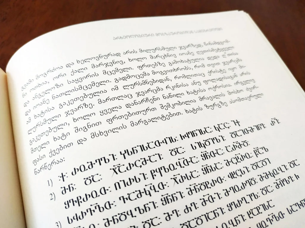 A book page mixes modern Mkhedruli with the older Asomtavruli capital letters.