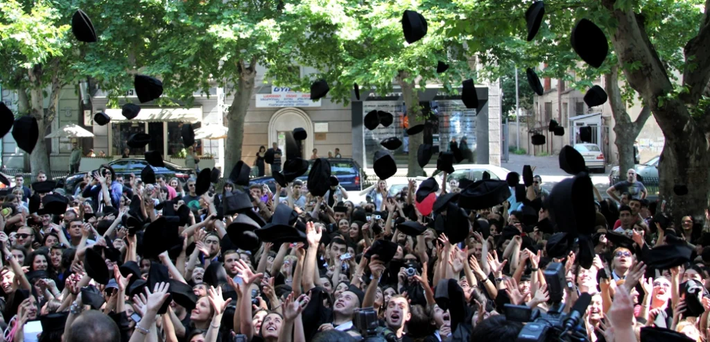 Graduation day celebration with students throwing caps at Ilia State University.