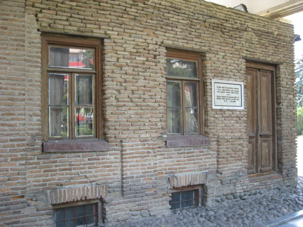 The small brick house where Stalin was born, now enclosed within the museum complex.