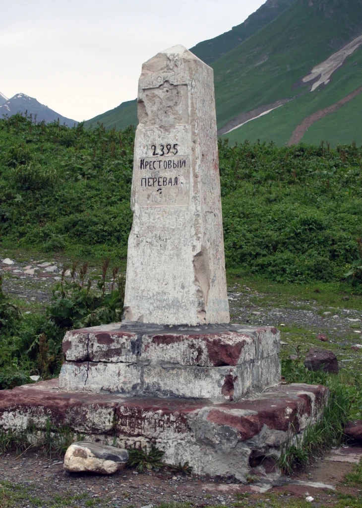 The old stone milestone reading '2395' marks the historic Krestovy (Jvari) Pass summit.