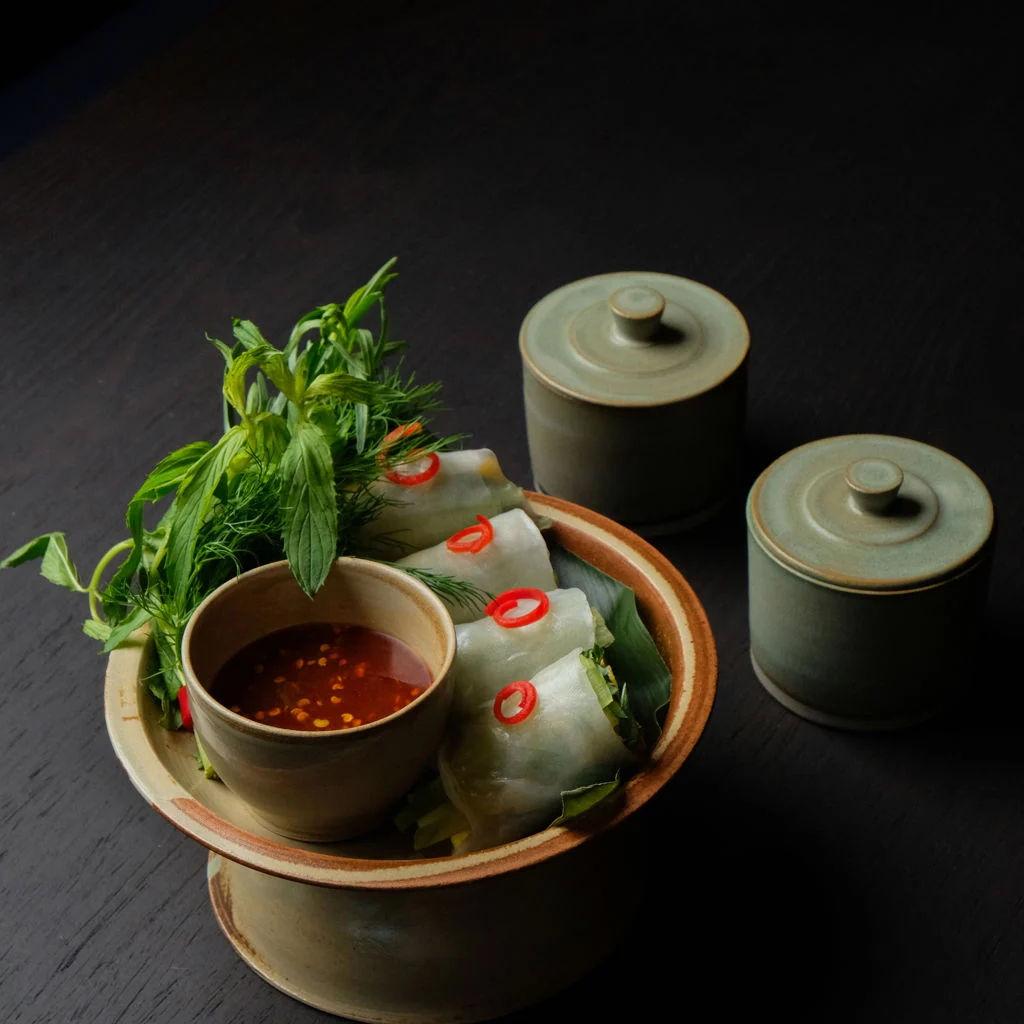 Laan Thai — свежие роллы из рисовой бумаги с соусом для макания и зеленью на керамической тарелке.