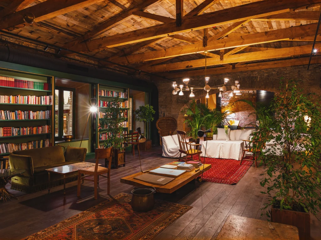Library Bar — Уютная библиотечная гостиная со встроенными книжными полками, мягкими креслами и декоративной люстрой.