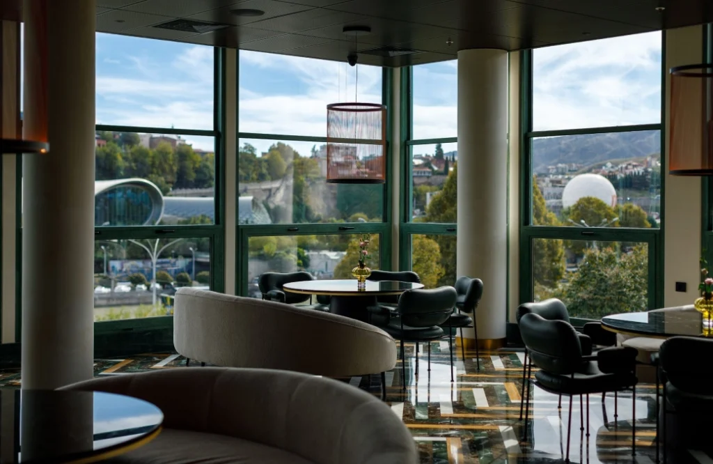 MOZAIKO — Modern restaurant seating area with floor-to-ceiling windows overlooking the city and river.