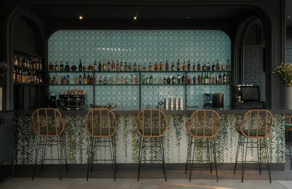 Mozaiko Terrace — Stylish bar area with patterned tile wall and rattan stools.