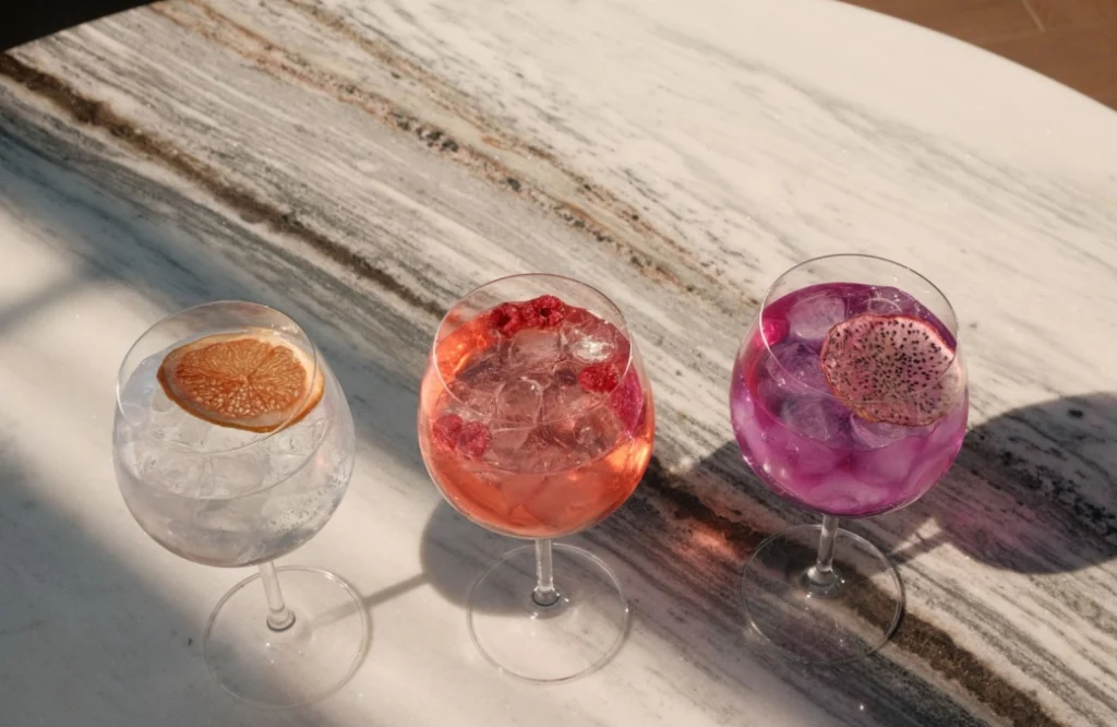 Mozaiko Terrace — Three colorful cocktails served on a marble table in sunlight.