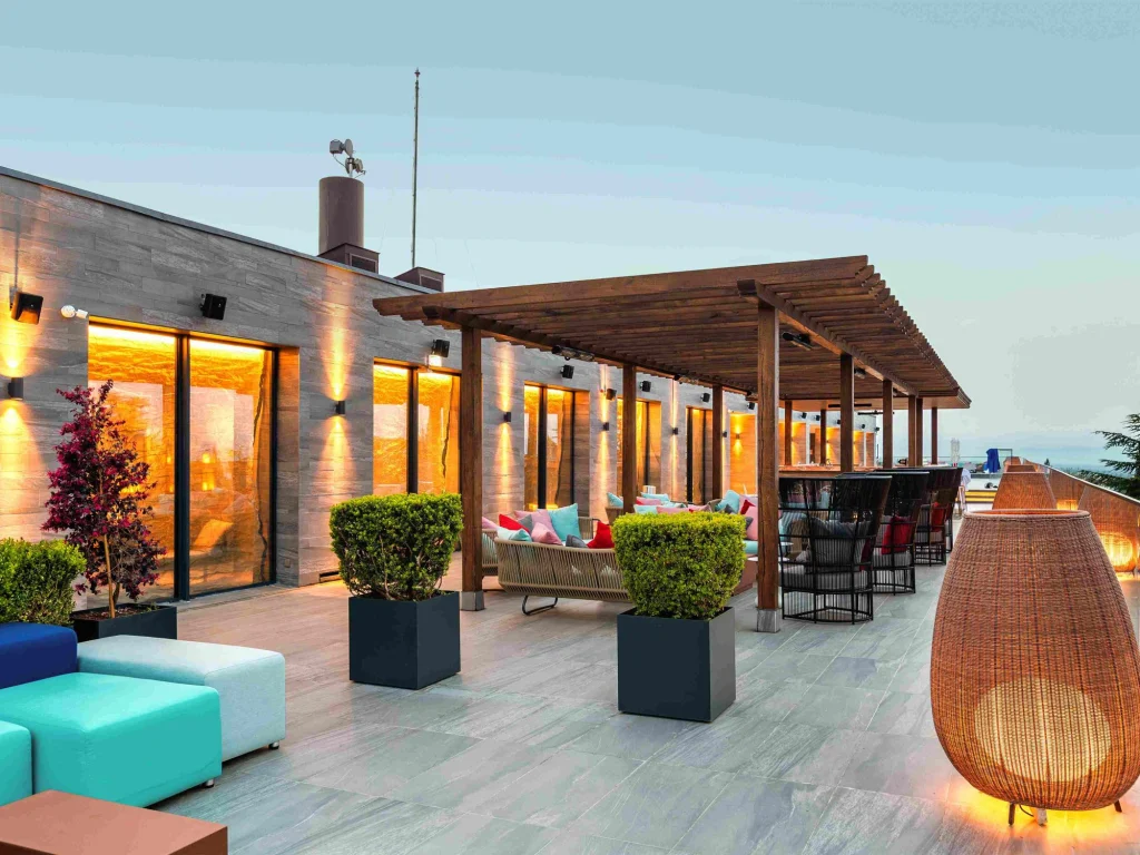 Pool Bar — терраса бара на крыше с тёплым освещением и яркой мебелью в сумерках.