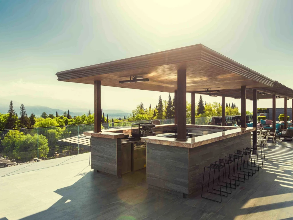 Pool Bar — барная стойка на открытом воздухе с высокими стульями под деревянным навесом на закате.